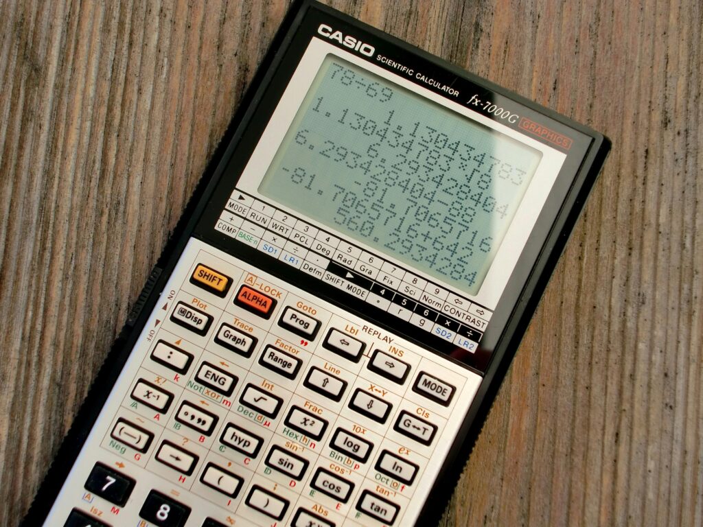 Kalkulator naukowy Casio na drewnianym blacie – strona do obliczania średniej, wyników i podstawowych działań matematycznych